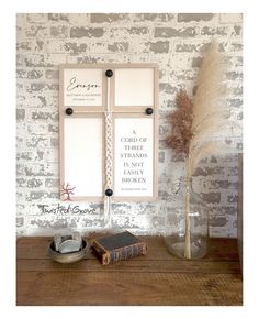 a table topped with a vase filled with flowers next to a wall mounted photo frame