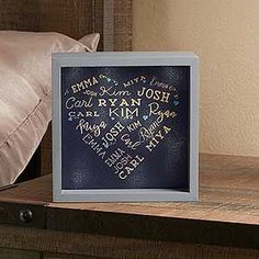 a framed cross stitch heart is sitting on a table next to a pillow and pillows