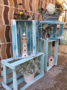 two wooden crates with flowers in them and a lighthouse on the shelf next to it