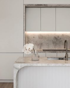 a kitchen with marble counter tops and white cabinets, along with a sink in the center