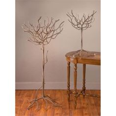 two metal tree sculptures sitting on top of a wooden table