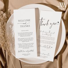 two folded wedding thank cards on a plate with some dried grass in the middle and an elegant script that reads, welcome and thanks