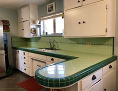 a kitchen with green counter tops and white cabinets