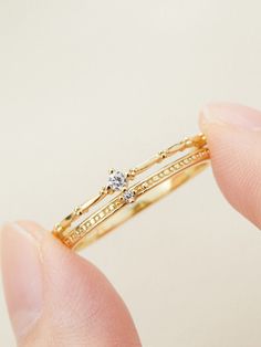 a person is holding a gold ring with a diamond on the top and bottom, in their hand