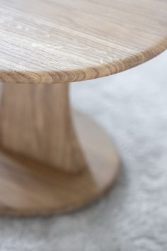 a round wooden table sitting on top of a carpeted floor