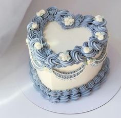 a heart shaped cake with blue icing and white flowers