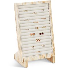 a wooden display case with six pairs of rings on it's front and two rows of earrings in the back