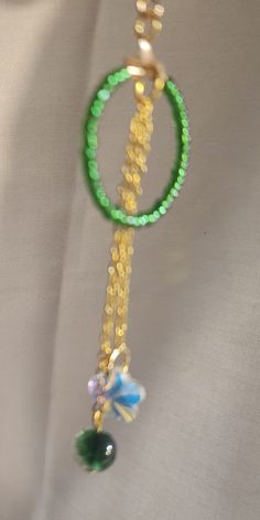 Green glass seed beads make the hoop hanging  from a gold earring hook pop.  Hanging from the center are two dainty gold colored chains holding a sparkling crystal on one ... Glass Jewelry With Dangling Beads For Party, Gold Glass Jewelry With Dangling Beads, Party Jewelry With Dangling Glass Beads, Dainty Green Beaded Chain Jewelry, Green Round Jewelry With Tiny Beads, Green Jewelry With Tiny Beads, Gold Dangle Beaded Necklace With Colorful Beads, Green Dangle Beaded Necklaces With Faceted Beads, Gold Beaded Necklaces With Czech Glass And Dangling Beads