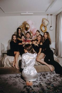 a group of women sitting on top of a bed in front of balloons and confetti