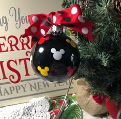 a christmas ornament hanging from the side of a tree with a red bow