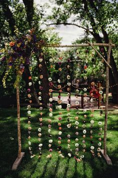 an outdoor ceremony setup with flowers and greenery hanging from the branches, in front of trees