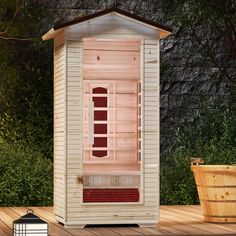 a small wooden sauna sitting on top of a wooden deck next to a potted plant