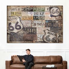 a man sitting on top of a brown couch in front of a wall covered with signs