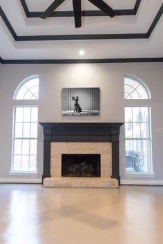 an empty living room with a fireplace and large windows