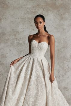 a woman in a strapless wedding dress poses for the camera with her hand on her hip