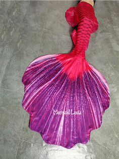 a woman in red and pink mermaid tail costume standing on the floor with her legs spread out