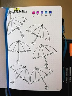 an open notebook with four umbrellas drawn on it and colored pencils next to it