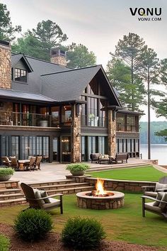 a large house sitting on top of a lush green field next to a fire pit