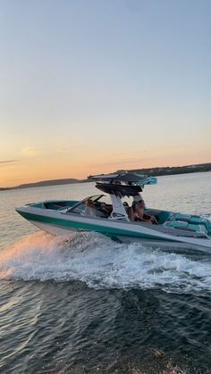 a motor boat with two people riding on the back in the water at sunset or dawn