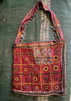 Item Details. This gorgeous slouchy handmade embroidered bag from Rajasthan in northern India, probably from the Banjara people. The bag has been made using an antique Indian embroidered madder dyed cotton with embroidered mirror decoration and beaded tassles along the handle, there is appliqué borders and lots of hand embroidered decoration. The bag has an attractive patch which has been added at a later date,made from a piece of contrasting embroidery. It has a hand quilted kantha stitched div Bohemian Pouch Shoulder Bag With Hand-stitched Details, Festival Tote Shoulder Bag With Hand-stitched Details, Rectangular Handwork Festival Bag, Bohemian Hand-stitched Tote Shoulder Bag, Bohemian Hand-stitched Bags, Bohemian Square Bags For Festivals, Festival Rectangular Bags With Multicolor Embroidery, Bohemian Hand-stitched Pouch Bag, Traditional Hand-stitched Tote Bag