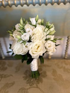 a bouquet of white flowers sitting on top of a table next to a chair and wall