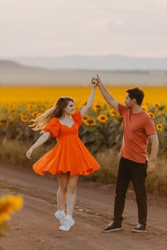 a man and woman holding hands in front of a sunflower field