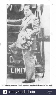 an old black and white photo of a man standing in front of a fire truck