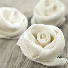 three small white roses sitting on top of a wooden table