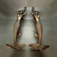 two bronze mermaid figurines sitting next to each other