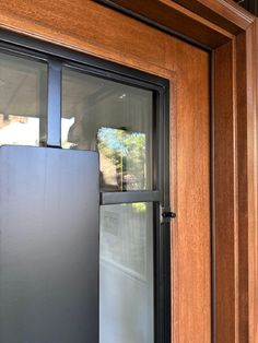 a metal refrigerator sitting in front of a wooden door with glass panels on the side