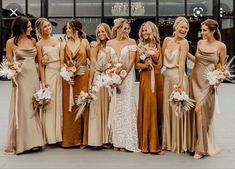 a group of women standing next to each other wearing dresses and holding bouquets in their hands