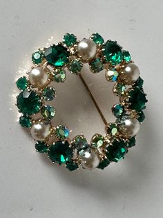 "A stunning vintage pearl with emeral green and aurora borealis rhinestone chatons layered wreath brooch. Two tiered brilliants. The aurora borealis stones reflect gold, blue and butter yellow. Gold plated setting. Though unsigned it is reminiscent of Montreal mid-century jewelers Continental, Jayflex and Sherman. The brooch measures 1 1/2 inches in diameter and 1/4\" deep incl. of pin mechanism In excellent vintage condition. Prices are listed for Canada and USA only but if you wish to have the Green Round Brooches For Wedding, Green Round Wedding Brooches, Wedding Jewelry Bride, Jewelry Bride, Of Montreal, Butter Yellow, Vintage Pearl, Christmas Pins, The Aurora