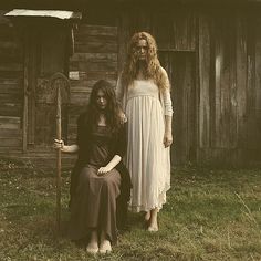 two women standing next to each other in front of a wooden building with the word interest on it