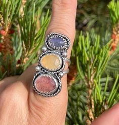 This ring features a unique color combination with a pinky-red Strawberry Quartz, Yellow Aventurine, and Blue Tanzanite set in a handcrafted .925 Sterling Silver design with twist borders and embellishments. The ring has a split shank style and is a Size 7 US.  IG: @wildrose.silver Please messsage me about custom sizing and gemstones! Multicolor Ruby Ring Gift, Multicolor Oval Ruby Ring Gift, Multicolor Oval Ruby Ring For Gift, Multicolor Natural Stone Rings For Anniversary, Anniversary Rings With Multicolor Natural Stones, Adjustable Rainbow Gemstone Ring, Unique Multicolor Opal Gemstone Ring, Adjustable Multi-stone Moonstone Ring Gift, Handmade Rainbow Colored Ring Jewelry