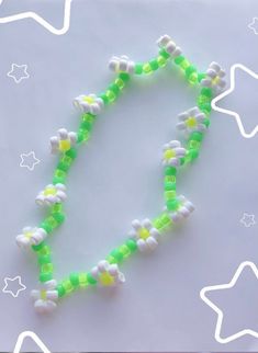 a green and white beaded necklace with stars on the bottom is laying on a table