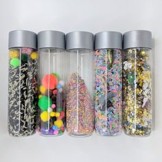 a row of glass jars filled with different types of confetti and sprinkles