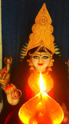 a woman holding a lit candle in her hand and wearing an elaborate headdress