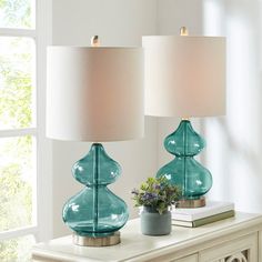 two glass lamps sitting on top of a white table