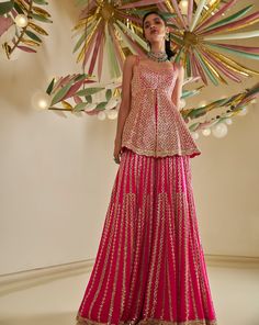 This sharara set features intricate gota patti embroidery on a fuchsia georgette base. The peplum top is paired with a flowy sharara and a four-sided embroidered dupatta.From Seema Gujral's Fiori - the sharara edit collection. DELIVERY TIMEPlease allow 8-12 weeks for your outfit to arrive. FABRIC DETAILSGeorgette Professional cleaning only. Sharara And Peplum Top, Peplum Top With Sharara For Wedding, Peplum Kurti Designs, Pink Indo Western Dresses, Sharara Set For Women, Mehandi Outfits Bridesmaid, Peplum Top Outfits Indian, Peplum Top With Sharara, Sharara Suit Designs Latest