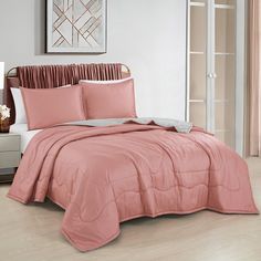 a bed with pink sheets and pillows in a room