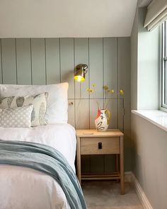 a white bed sitting next to a window with yellow flowers in vases on top of it