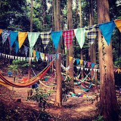 there are many colorful flags hanging in the woods