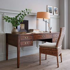 a wooden desk topped with a lamp next to a chair and a plant on top of it