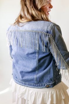 This jacket has style that is out of this world! It includes an medium wash, long sleeves, button up front, collared neck, and a strand of rhinestone fringe that runs across the back and down the back of the sleeves. Pair this with a tank top and Charlie 1 Horse hat and you'll be set! Abby is wearing a size large. Size Suggestions: Small: 2-6 | Bust: 20 inches across | Length: 21.5 inches Medium: 8-10 | Bust: 21 inches across | Length: 22 inches Large: 12-14 | Bust: 22 inches across | Length: 22 Spring Denim Jacket With Beaded Fringe And Long Sleeves, Fitted Long Sleeve Outerwear With Rhinestone Fringe, Fall Denim Jacket With Beaded Fringe And Long Sleeves, Beaded Fringe Long Sleeve Outerwear For Spring, Long Sleeve Denim Jacket With Rhinestone Fringe, Trendy Beaded Fringe Fall Outerwear, Trendy Spring Denim Jacket With Rhinestone Fringe, Long Sleeve Outerwear With Beaded Fringe For Spring, Trendy Denim Jacket With Rhinestone Fringe For Fall