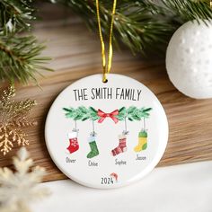 a personalized christmas ornament hanging from a pine tree with stockings on it