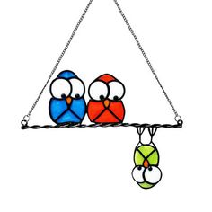 two colorful birds sitting on top of a metal chain hanging from a ceiling light fixture