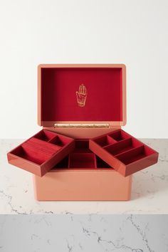 an open pink box with four compartments and a gold hand print on the lid, sitting on a marble countertop