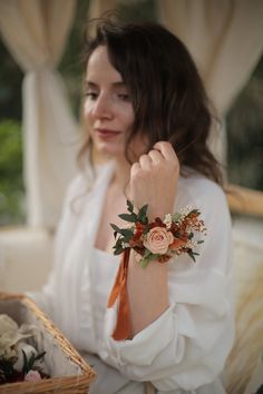 a woman sitting on a couch holding onto a flower bracelet