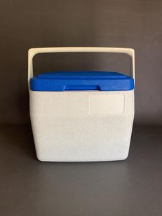 a white and blue cooler sitting on top of a black table next to a wall