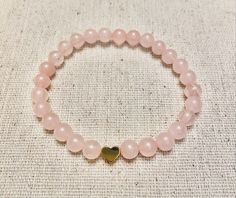 "This sweet little bracelet uses 6mm Rose Quartz beads & you can choose between a gold, silver, or black heart.  This bracelet is made to order. When selecting your size, measure your wrist at the smallest point & then add 1/4\"-1/2\" for comfort. Please message me if you need any customizations. :-)  Listing is for one bracelet." Rose Gold 8mm Beads Bracelet As Gift, Rose Gold Bracelets With 8mm Beads For Gift, Rose Gold 8mm Beads Bracelet For Gift, Elegant Heart Beads Stretch Bracelet Gift, Elegant Heart Beads Stretch Bracelet For Gift, Elegant Round Beads Stretch Bracelet For Valentine's Day, Elegant Rose Gold Heart Beaded Bracelets, Elegant Heart-shaped 8mm Beads Bracelet, Elegant Heart-shaped Bracelets With 8mm Beads